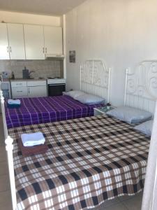 twee bedden in een kamer met paarse lakens en een keuken bij Breeze Apartments in Perea