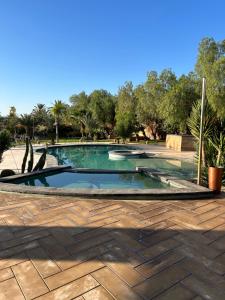 a swimming pool in a yard with trees in the background at Villa Madina in Dar Caïd Layadi