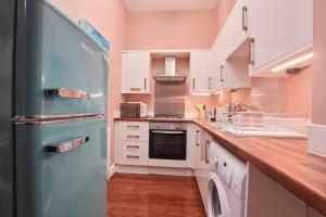 a kitchen with white cabinets and a blue refrigerator at Lovely Chique Newcastle Abode - Sleeps 4 in Elswick