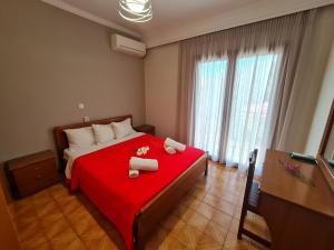 a bedroom with a red bed with two towels on it at Zigos Apartments in Igoumenitsa