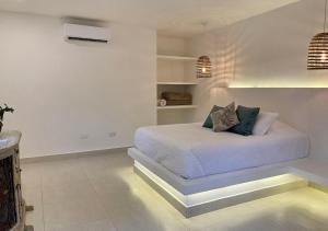 Dormitorio blanco con cama con almohadas en Hotel La Finca Buritaca by DOT Premium en Buritaca