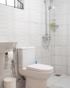 a white bathroom with a toilet and a shower at Andrella Home Arusha in Arusha