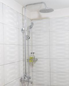 a shower in a bathroom with white tiles at Andrella Home Arusha in Arusha