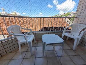two chairs and a table on a balcony at Apto aconchegante quarto e sala reversível in São Lourenço