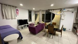 un soggiorno con divano viola e tavolo di Círculos del Lago a Villa Carlos Paz
