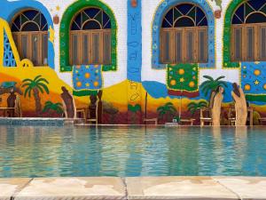 a building with a swimming pool with a mural at Kato Dool Wellness Resort in Aswan