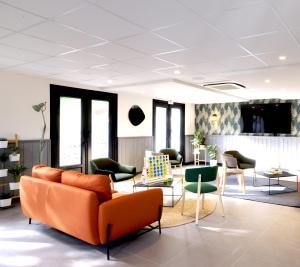 un vestíbulo de oficina con sofá naranja y sillas en Campanile Limoges Nord, en Limoges