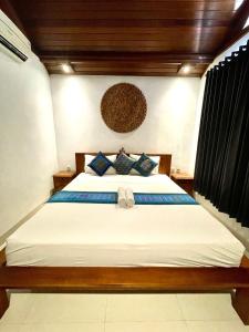 a bedroom with a large white bed with blue pillows at DIMUWA Ubud in Ubud