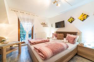 a bedroom with a large bed with pink sheets at Penzión Zunama in Bardejovské Kúpele