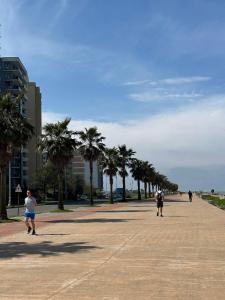 a group of people walking down a sidewalk with palm trees at GOOD-VIBES Apartments in Batumi +5 photos