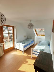 a bedroom with two beds and a table and a window at Ferienwohnung mit Dachterrasse in Achberg