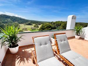 Un balcón con 2 sillas y vistas. en Apartamento Atardecer en Menorca Son Parc Vista al campo de golf, en Son Parc