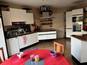 a kitchen with a red table and a kitchen with white cabinets at Gazonfier in Le Mans