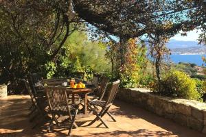 a table and chairs on a patio with a view of the water at Villas Valinco San Martinu Corse du Sud - vue et proche mer - piscines-7 chambres in Olmeto