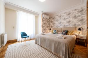 um quarto com uma cama grande e uma cadeira azul em Belle Epoque on the Seafront em San Sebastián
