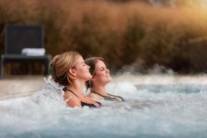 zwei Frauen, die in einem Whirlpool im Wasser liegen in der Unterkunft Parkhotel Bad Arcen in Arcen
