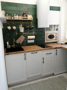 a kitchen with white cabinets and green tiles at Hanna apartman in Szeged