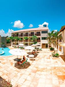 ein Resort mit einem Pool, Stühlen und Sonnenschirmen in der Unterkunft Estação do Sol Praia Hotel in Porto De Galinhas