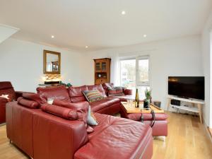 a living room with red leather furniture and a flat screen tv at Generals Yard in Eyemouth