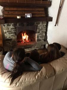 a group of people laying on a couch in front of a fireplace at Baita Palue in Torcegno