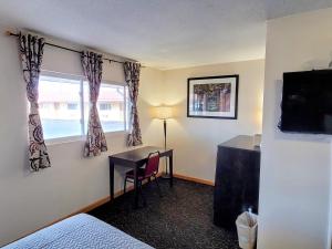 a hotel room with a desk and a window at Woodland Inn in Niagara Falls