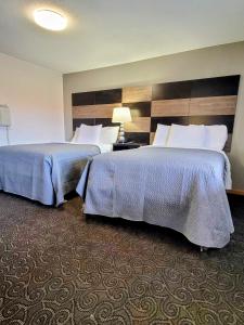 a hotel room with two beds and a lamp at Woodland Inn in Niagara Falls