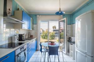 una cocina con armarios azules y una mesa con sillas en Le Maréchal Juin - Appt 8 voyageurs, en Perpiñán