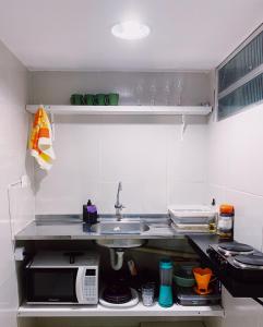 a small kitchen with a sink and a microwave at Studio Aurora - Recife in Recife