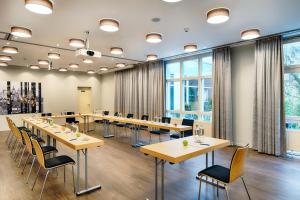 una sala de conferencias con mesas, sillas y ventanas en Welcome Hotel Marburg, en Marburg an der Lahn