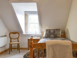 ein Schlafzimmer mit einem Bett, einem Stuhl und einem Fenster in der Unterkunft Annies Cottage in Edinbain