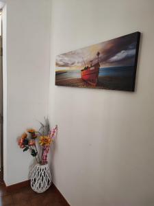 een schilderij van een boot op een muur met een vaas van bloemen bij Casa Limone in San Pietro in Bevagna