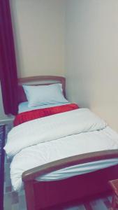 a bed with white sheets and a red blanket at Jordanian Baity Apartment in Wadi Musa