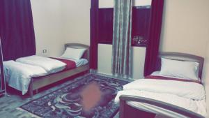 two beds in a room with purple curtains at Jordanian Baity Apartment in Wadi Musa