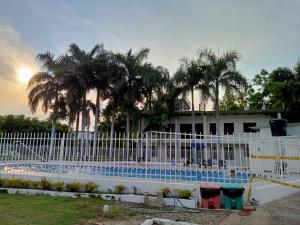 uma cerca branca em torno de uma piscina com palmeiras em Casa Entre Los Arboles +Jacuzzi +Piscina em Nariño