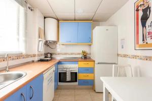 La cuisine est équipée de placards bleus et d'un réfrigérateur blanc. dans l'établissement LUNAROOM Center & Quiet Guesthouse, à Malaga