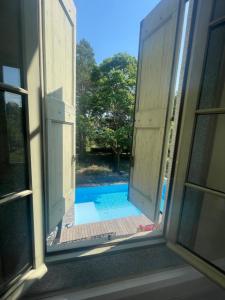 une fenêtre ouverte avec vue sur la piscine dans l'établissement Le Lodge Saissac, à Saissac