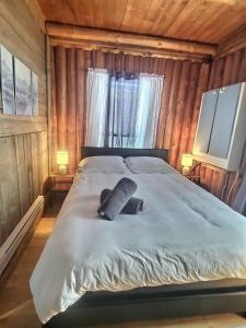 a bedroom with a bed with two pillows on it at Nelson Warm Log Cabin with Private Hot Tub in Rivière-Rouge