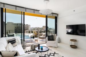 a living room with white furniture and a large window at Bright & Chic Condo with Pool & Unique View by FeelHome in Tel Aviv