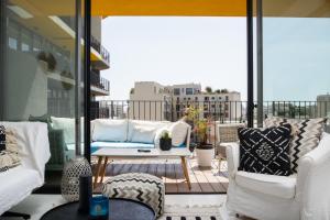 a balcony with white couches and a table at Bright & Chic Condo with Pool & Unique View by FeelHome in Tel Aviv