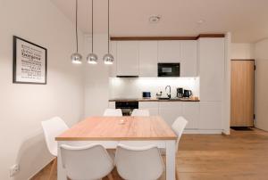 a kitchen and dining room with a wooden table and white chairs at Aura 40 by Q4Apartments in Gdańsk