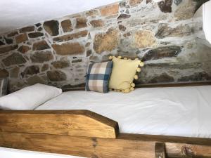 a bed with two pillows and a stone wall at Casa Da Oliveira in Pedrógão Grande