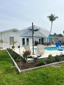 a house with an umbrella and a swimming pool at Turtle Island - Family Friendly Pool Home -Welcome in Naples