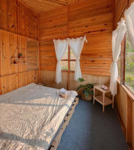 a bedroom with a bed in a wooden cabin at Nguyên căn - Góc sân và Khoảng trời Dalat Homestay in Ấp Phước Thánh