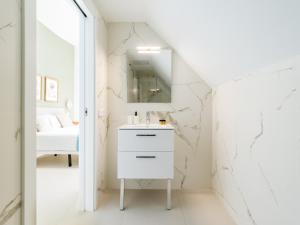Baño blanco con lavabo y espejo en Royal Suites, en Las Palmas de Gran Canaria