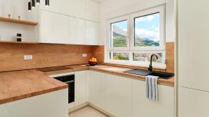 Una cocina con gabinetes blancos y un fregadero y una ventana. en Villa AdriaStar by Villas Holiday, en Dugi Rat
