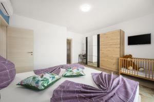 1 dormitorio con cama con almohadas moradas y cuna en Villa Nur Pula, en Pula