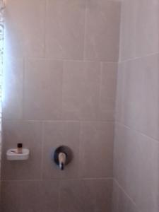 La salle de bains est pourvue d'une douche carrelée avec un robinet. dans l'établissement Sunshinevibe guest house, à Kasane