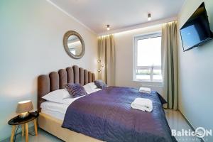 1 dormitorio con 1 cama con edredón morado y TV en Apartamenty BalticON Westin House en Kołobrzeg