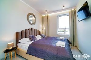 コウォブジェクにあるApartamenty BalticON Westin House -luksusowy 70m2 , basen pool, sauna, parking inklusiveのベッドルーム1室(紫色の掛け布団、テレビ付) +61枚の写真
