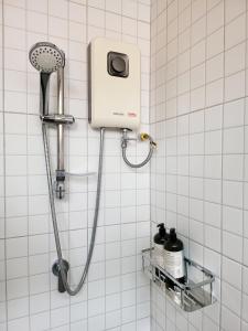 La salle de bains est pourvue d'une douche et de carrelage blanc. dans l'établissement Baby Come Home, à Chiang Mai